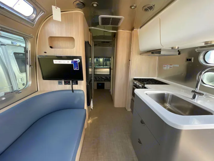 Airstream rv rental interior: Modern kitchen, living area with TV & comfy curved seating. Perfect for your next trip.. Airstream Globetrotter 2024
