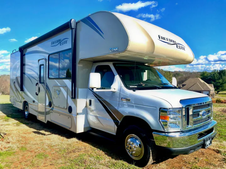 This white and gray Thor Freedom Elite Class C RV rental is parked outdoors on a sunny day, ready for adventure.. Thor Freedom Elite 2018