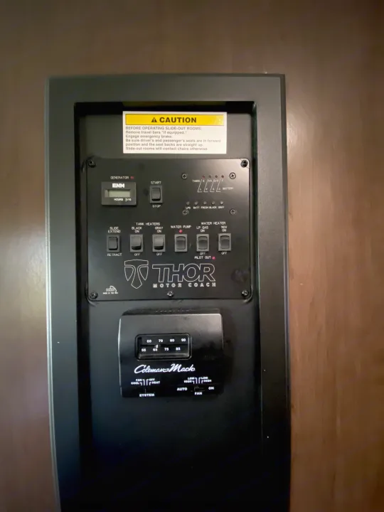 This RV rental control panel shows generator, tank, water, and slide-out controls, plus a Coleman-Mach thermostat.. Thor Freedom Elite 2018