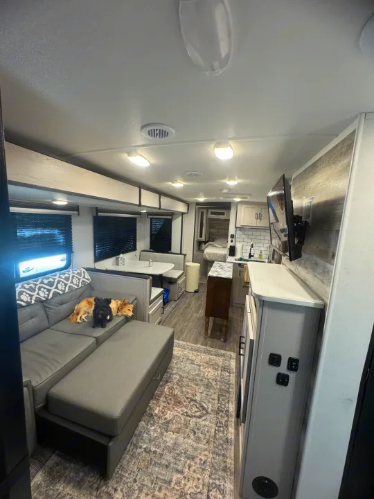 Inside a modern RV rental: a cozy living area with two dogs, dining space, kitchenette, and bedroom in a bright interior.. Heartland RVs Mallard 2024