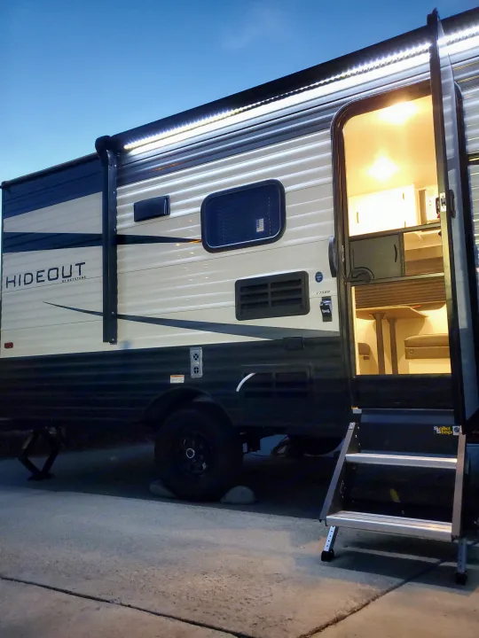 Explore this bright rv rental! A Keystone Hideout travel trailer with inviting interior lights and exterior awning lights on.. Keystone RV Hideout 2021