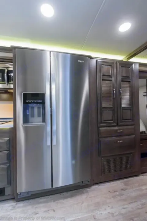 Spacious RV rental kitchen with a large stainless steel Whirlpool refrigerator and ample dark wood cabinetry.. Entegra Coach Accolade 2023