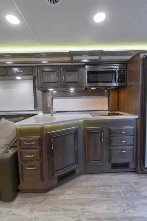 Spacious RV rental kitchen with modern gray cabinets, microwave, sink, and stovetop, perfect for on-the-go cooking.. Entegra Coach Accolade 2023