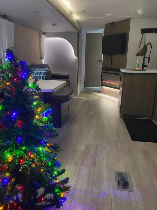 Cozy RV rental interior with a festive Christmas tree, showing the living area, kitchen, and fireplace.. Forest River Salem 2025