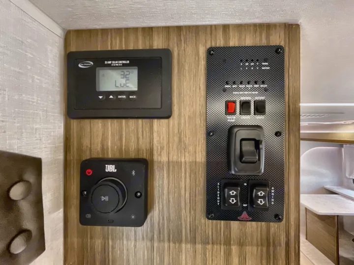 Interior RV rental control panel: solar, JBL audio, tank levels, water pump, slideout, and awning switches.. Forest River Salem 2025