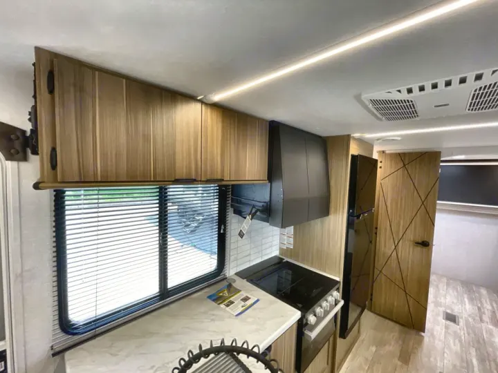 Explore this clean, modern RV rental interior, showcasing a full kitchen with stove, fridge, and ample storage, ideal for your next trip.. Forest River Salem 2025