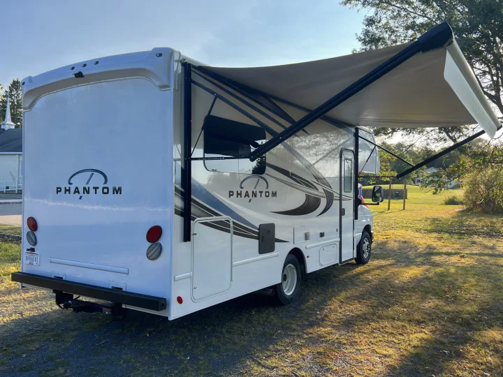 White Phantom RV rental with awning extended, parked on a sunny day. Ready for your next travel adventure.. Nexus Phantom 2025