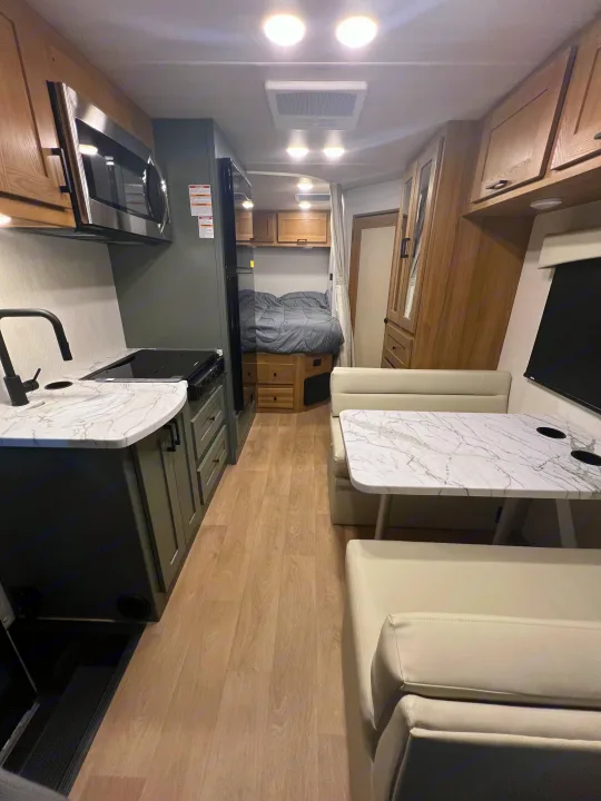 Explore this cozy rv rental interior: a modern kitchen, comfortable dinette, and bed area for your travels.. Nexus Phantom 2025