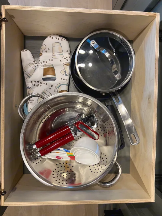 RV rental kitchen drawer neatly packed with cookware, measuring tools, and an oven mitt for camping meals.. Nexus Phantom 2025