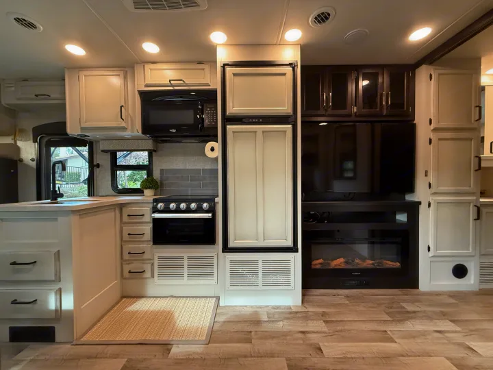 Spacious RV rental interior featuring a modern kitchen with appliances and a living area with TV and fireplace.. Jayco Greyhawk 2023