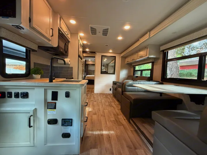 This clean, modern RV rental interior offers a fully-equipped kitchen, comfortable sofa, and dining area, ready for your next travel adventure.. Jayco Greyhawk 2023