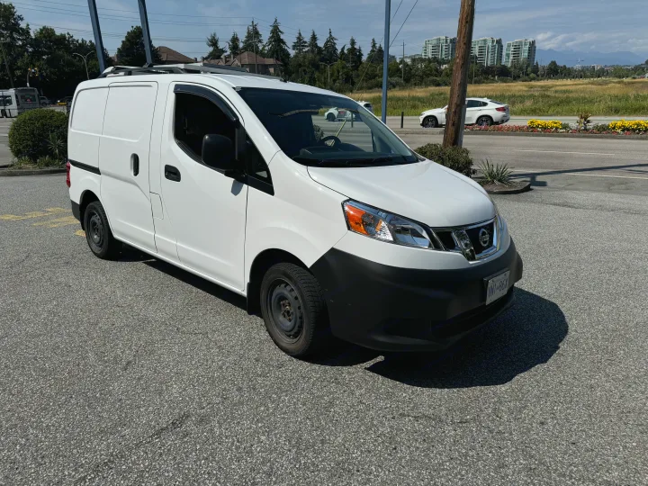 A white Nissan NV200 cargo van with roof rack, ideal for work or a potential compact rv rental conversion.. Nissan NV200 2015
