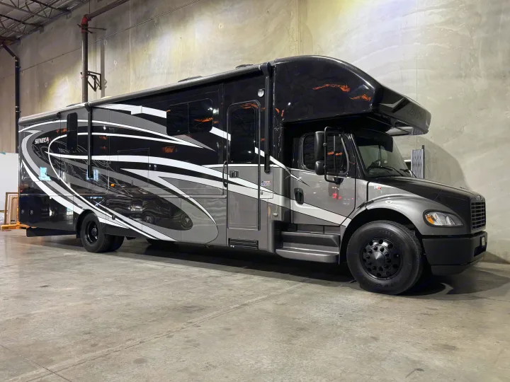 A sleek black & gray Jayco Seneca motorhome, ideal for rv rental, is parked indoors on a concrete floor.. Jayco Seneca 2020