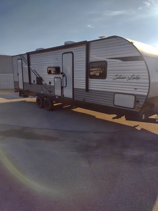 Modern Silver Lake travel trailer available for rv rental. This two-axle RV has silver/grey exterior, parked on asphalt.. East to West Silver Lake 2021