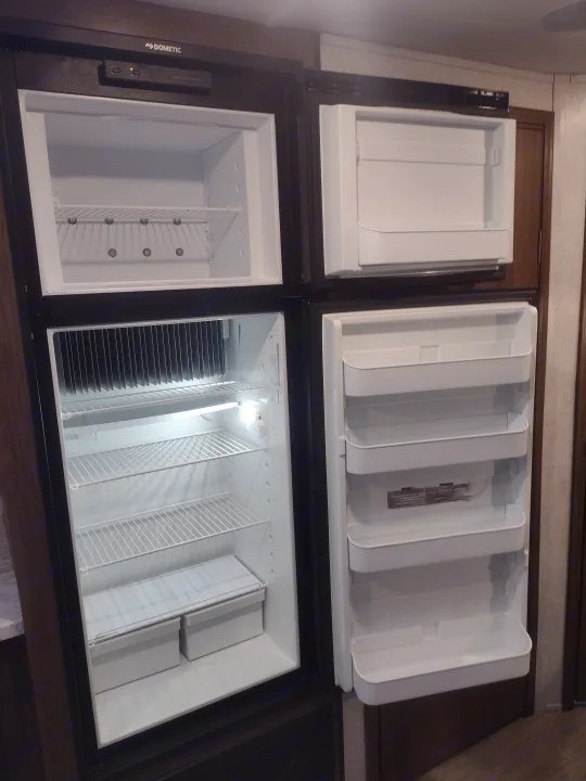 Large Dometic RV refrigerator/freezer open, ready for an RV rental adventure. Spacious interior with shelves and door bins.. East to West Silver Lake 2021