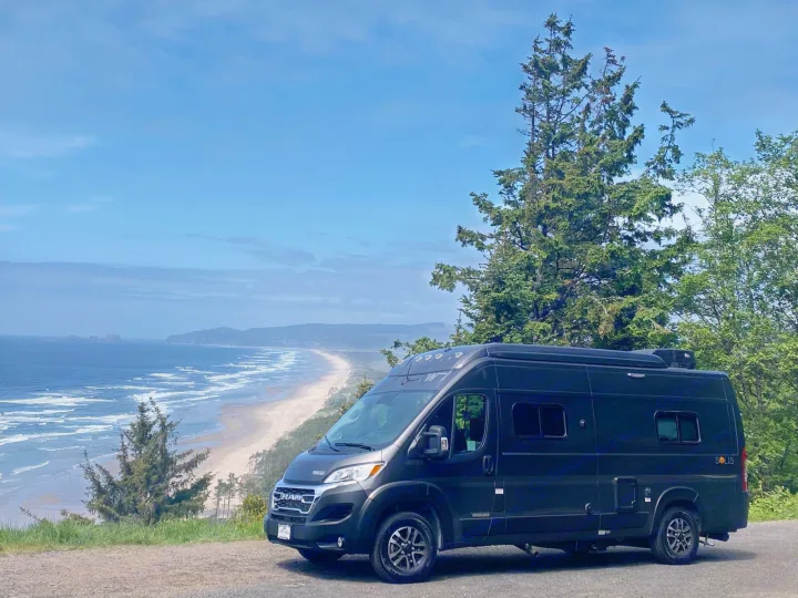Explore the coast! A black RV rental overlooks a beautiful beach and ocean vista under a blue sky.. Winnebago Solis 59PX 2025