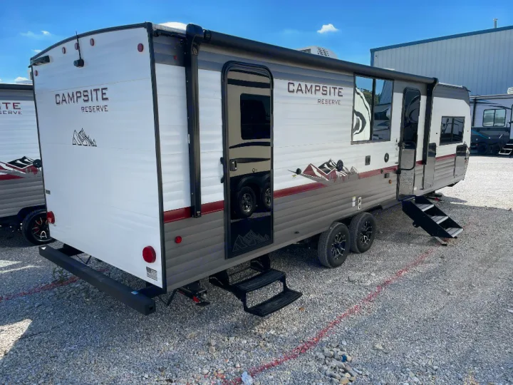 Modern white and gray travel trailer with steps, ideal for an RV rental vacation. Parked on gravel, ready for camping adventures.. Forest River Campsite Reserve 2025