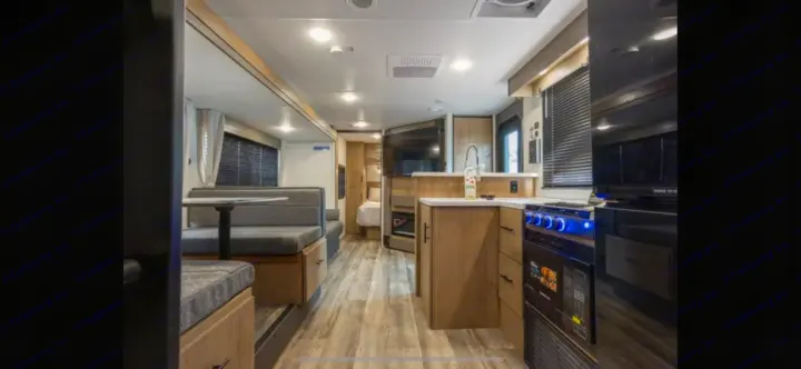 Explore this spacious rv rental interior, featuring a modern kitchen, comfortable dinette, and private bedroom area.. Forest River Campsite Reserve 2025