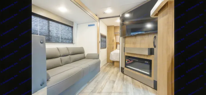 Modern RV rental living area with comfy sofa, TV, fireplace, and adjoining bedroom.. Forest River Campsite Reserve 2025