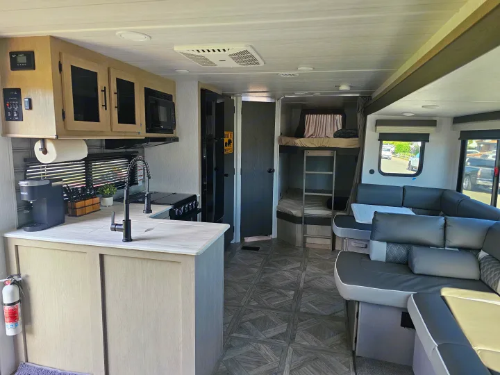 Spacious, modern RV rental interior with a full kitchen, L-shaped sofa, and bunk beds.. Forest River Salem 2024