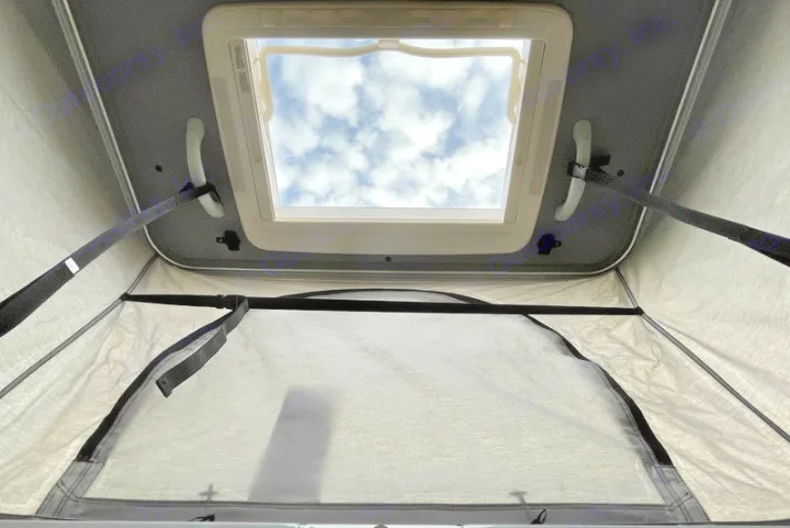 RV rental interior with an open pop-top skylight, revealing cloudy skies above the fabric walls.. Thor Scope 2023