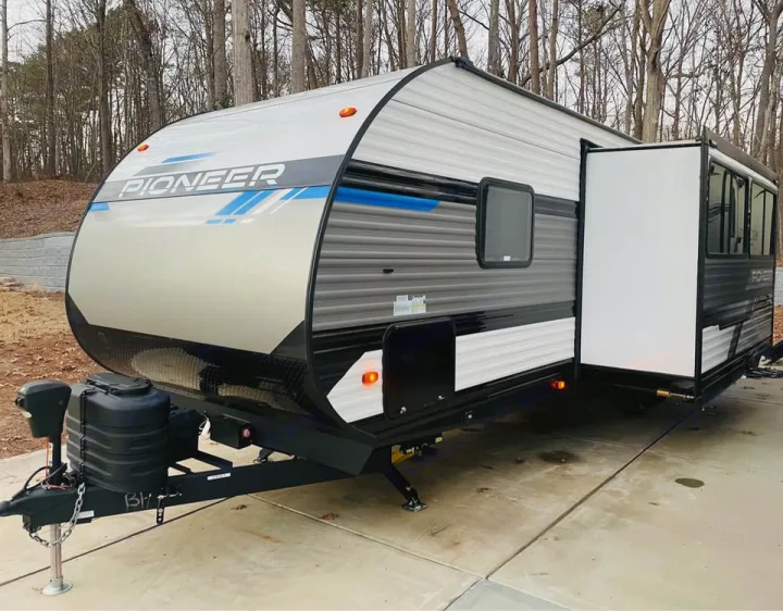 Gray and black Pioneer travel trailer, perfect for an rv rental adventure. This modern RV is parked on a concrete pad.. Heartland RVs Pioneer 2023