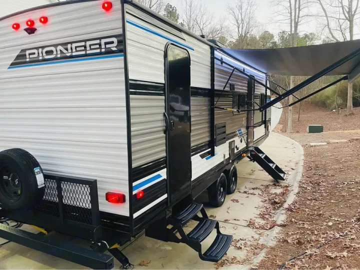 PIONEER travel trailer RV rental, featuring extended awning, deployed steps, and rear storage. Perfect for camping & road trips!. Heartland RVs Pioneer 2023