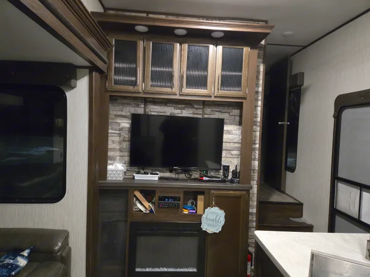 Experience comfort in this RV rental's living room, featuring a built-in TV, cozy fireplace, and ample storage.. Forest River Cherokee Arctic Wolf 2019