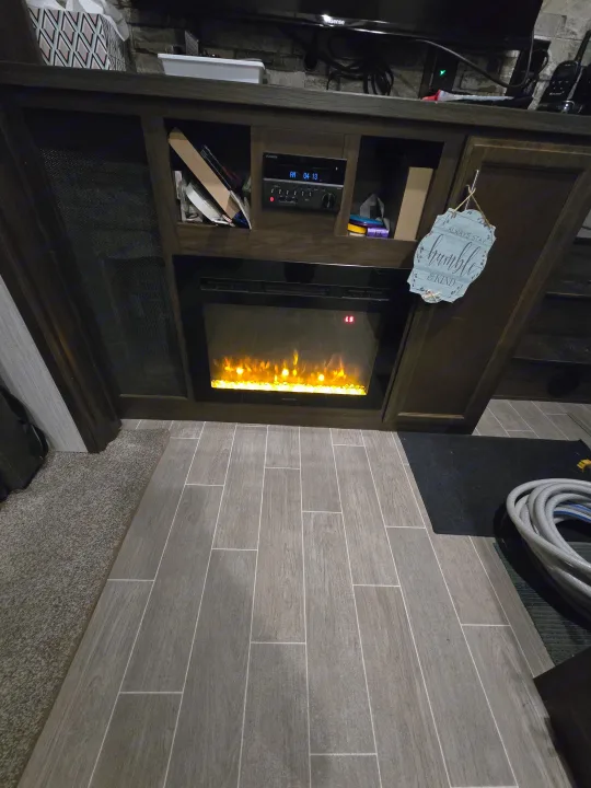 Inside an RV rental: a cozy living space with an electric fireplace, Furion media center, Hisense TV, and wood-look flooring.. Forest River Cherokee Arctic Wolf 2019