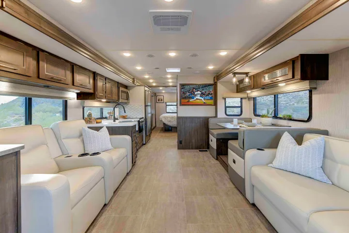 This modern RV rental features a spacious interior with light leather seating, a kitchen, dining booth, and TV.. Coachmen Mirada 35OS 2023
