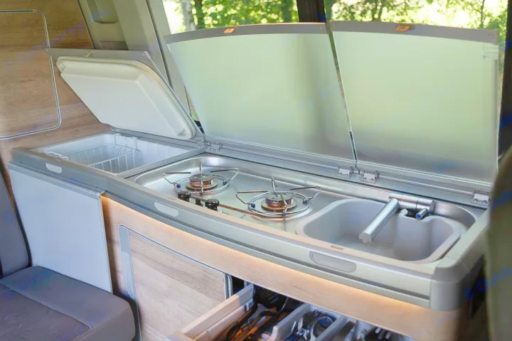 This RV rental's compact campervan kitchen has a fridge, two-burner stove, sink, and storage, ready for travel meals.. Volkswagen California Coast T6 2020