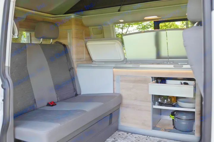 RV rental camper van interior: functional kitchen with open sink, fridge, comfortable seating, and organized storage cabinets.. Volkswagen California Coast T6 2020