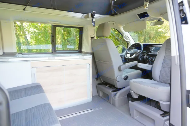 RV rental camper van interior showing front swivel seats, compact kitchen unit, rear bench, and a pop-top roof.. Volkswagen California Coast T6 2020