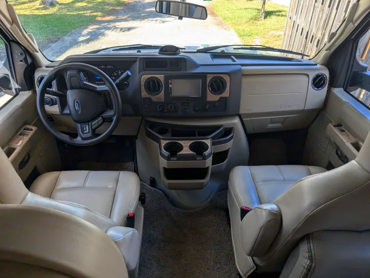 RV rental: Spacious RV front cabin showing the driver's view of the dashboard, steering wheel, and seats.. Thor Four Winds 2021
