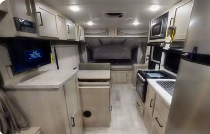 Bright RV rental interior features a full kitchen, dining area, and comfortable rear bed. Ideal for travel adventures.. Rockwood Roo 2022