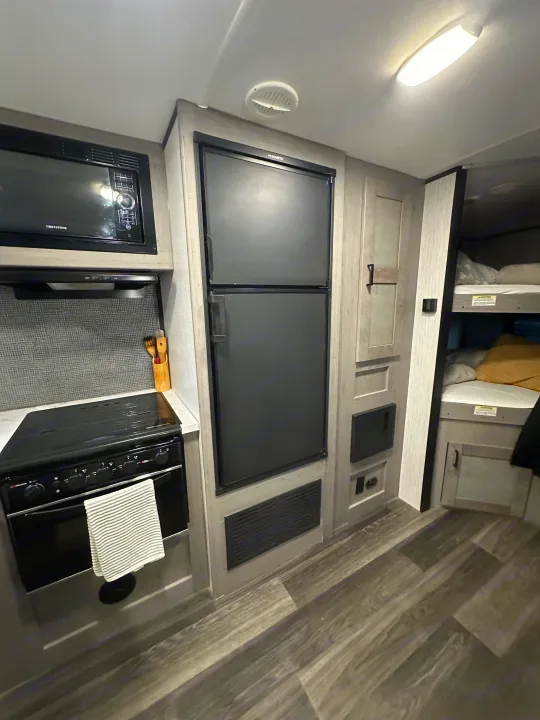 Explore this RV rental's modern interior: kitchen with microwave, stove, fridge, and cozy bunk beds perfect for your next adventure.. Heartland RVs Mallard 2022