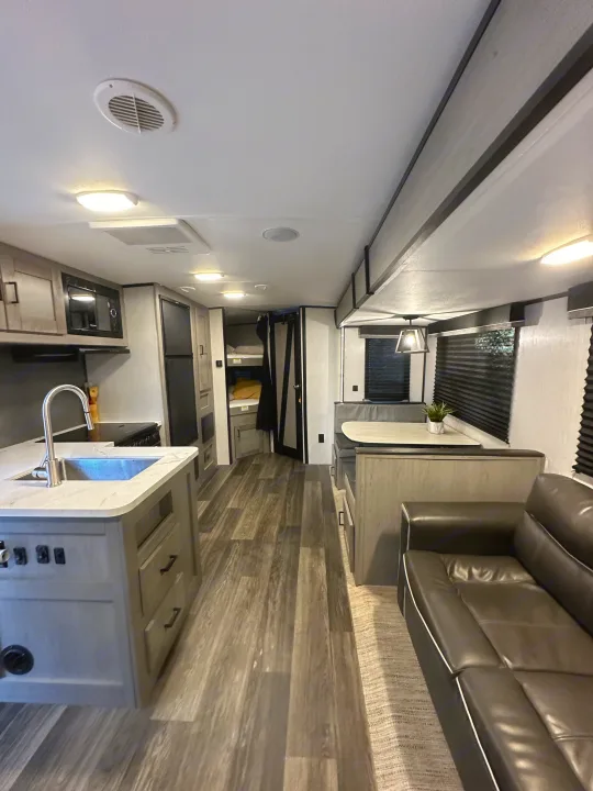 Spacious RV rental interior with kitchen, dinette, and bunk beds, offering a comfy living area.. Heartland RVs Mallard 2022