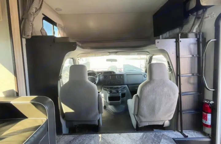RV rental interior: front cockpit with driver & passenger seats, overhead bunk bed, TV, and access ladder for your camper adventure.. Forest River Forester 2020