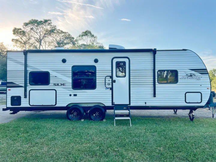 A white Jayco Jay Flight travel trailer RV rental, parked on grass at sunset. Ready for your camping adventure!. Jayco Jay Flight SLX 260BH 2025