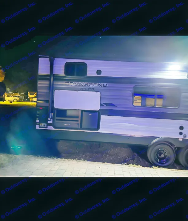 Nighttime view of a Transcend Xplor RV rental. Blue accent lighting highlights its sleek design and accessible outdoor kitchen.. Grand Design Transcend Xplor 2024