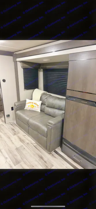 Cozy RV rental interior with a modern sofa, festive pumpkin pillow, and Furrion refrigerator. Ready for your adventure!. Grand Design Transcend Xplor 2024