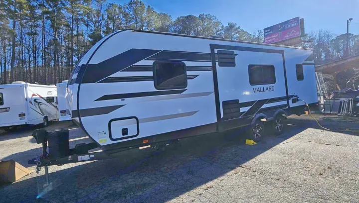 A sleek white and black Mallard travel trailer, perfect for your next rv rental adventure on the open road.. Heartland mallard 2022