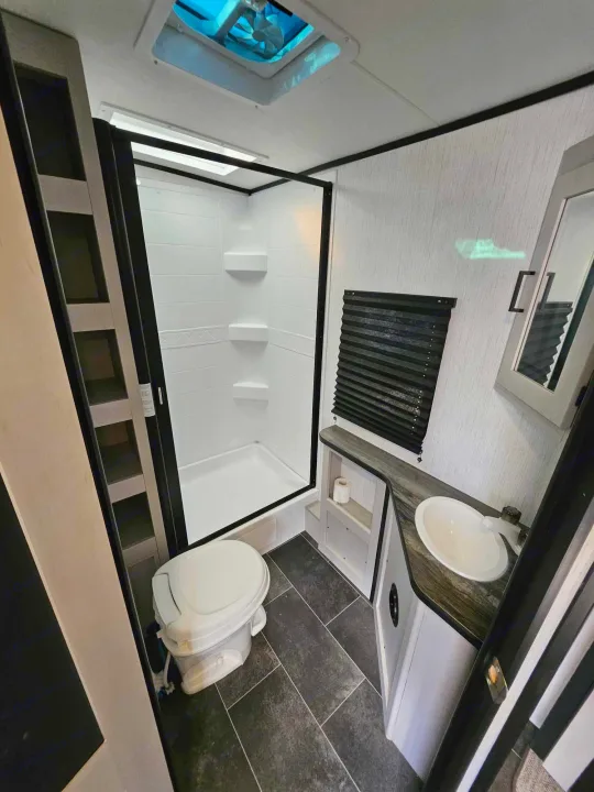 This RV rental features a modern, compact bathroom with a shower, toilet, and sink vanity, perfect for travelers.. Heartland mallard 2022