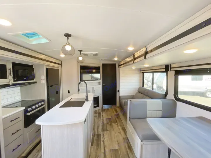 Spacious, modern rv rental interior featuring a kitchen island, dining booth, and comfortable living area with large windows.. Crossroads RV Sunset Trail Super Lite 2023