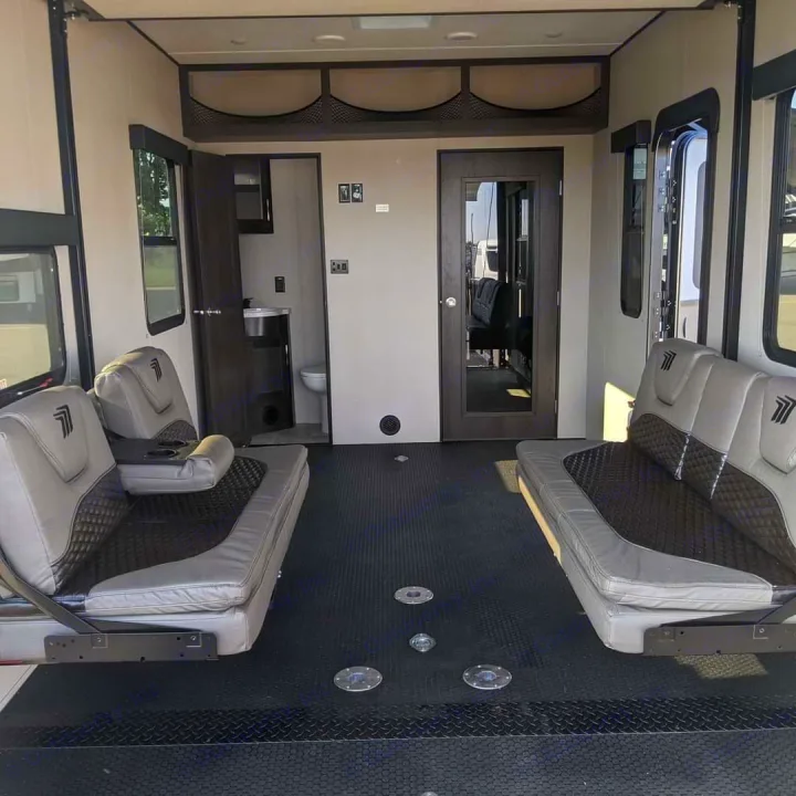 RV rental toy hauler interior: versatile rear lounge with convertible seating, durable floor, and bathroom access.. Grand Design Momentum Toy Hauler 2022