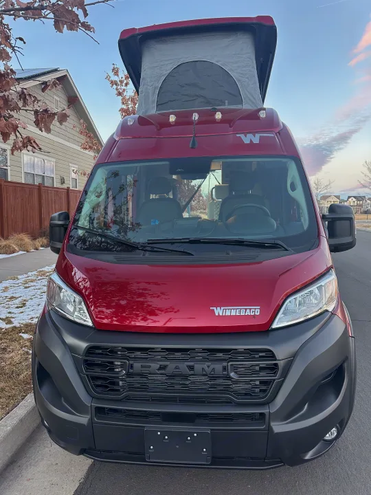 Front view of a red Winnebago pop-top camper van, ideal for an unforgettable RV rental trip.. Winnebago Solis 2023