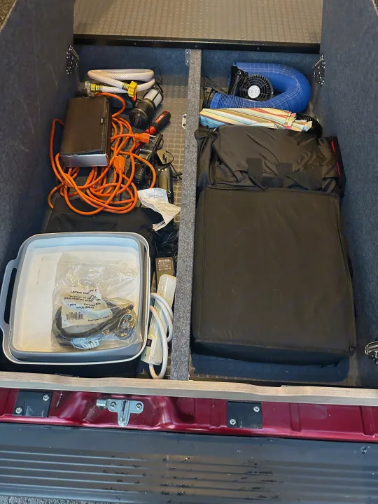 RV rental's rear storage, meticulously organized with hoses, power cords, fan, and essential camping gear.. Winnebago Solis 2023