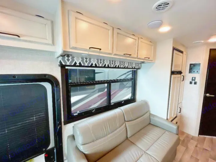 RV rental: Bright interior featuring a light-colored sofa, overhead cabinets, and a large window with patterned valance.. Entegra Coach 29F 2021