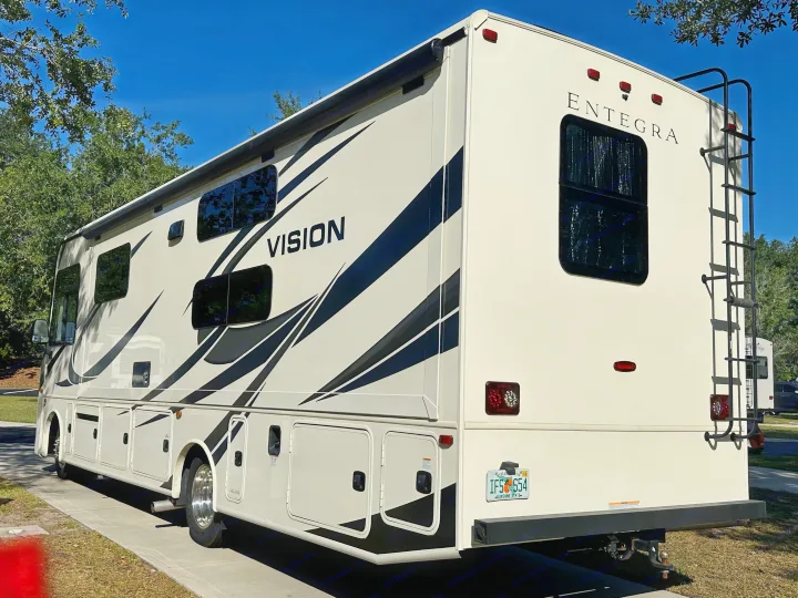 A cream Entegra Vision RV, great for rv rental, parked under a blue sky. This spacious motorhome is ready for travel adventures.. Entegra Coach 29F 2021