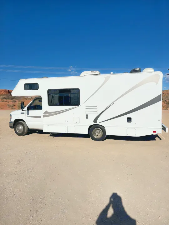 White RV rental parked on a desert road under a clear blue sky, perfect for your next adventure.. Thor Majestic 2018